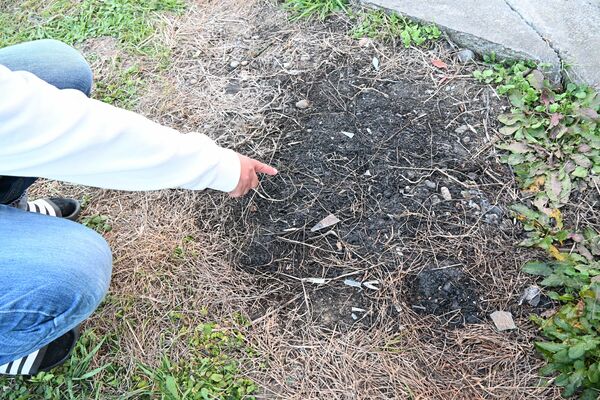 犯人に割られ、庭に飛散した窓ガラスの破片を指さす住人男性=12月上旬、小山市内