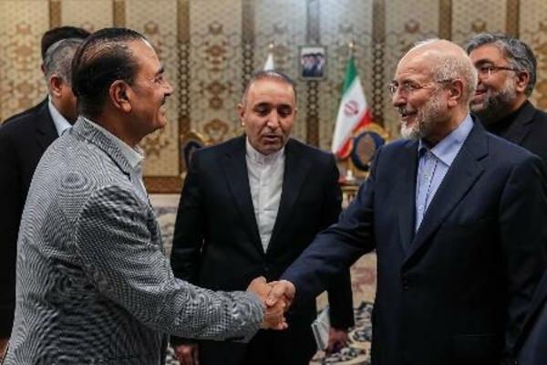 23日、イランの首都テヘランで、ガリバフ国会議長(右)と握手するパキスタンの軍トップ、ムニール陸軍元帥(イラン国会議長事務所提供・ゲッティ=共同)