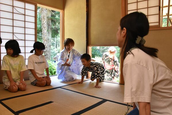 「にじり口」から茶室に入る子どもら