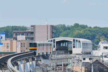 北の終点、上北台駅を出発する多摩モノレール。背後は狭山丘陵の森