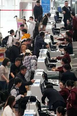 北京首都空港の日本便などを扱うカウンターで搭乗手続きをする人たち=15日(共同)