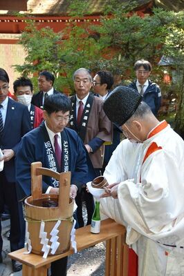 参列者に神水を分け与える中麿宮司（右）ら