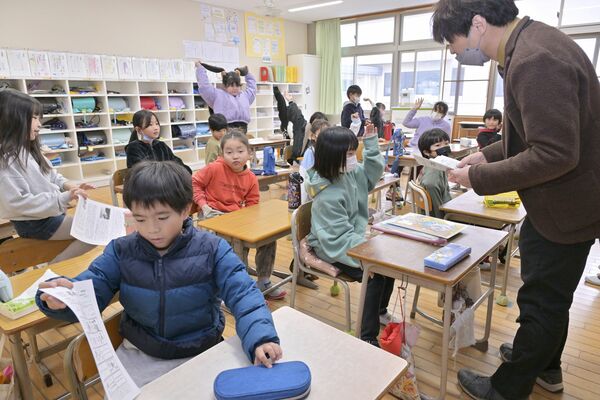 学校便りや冬休みの過ごし方などが書かれた配布物を受け取る児童＝25日午前11時30分、足利市福富町