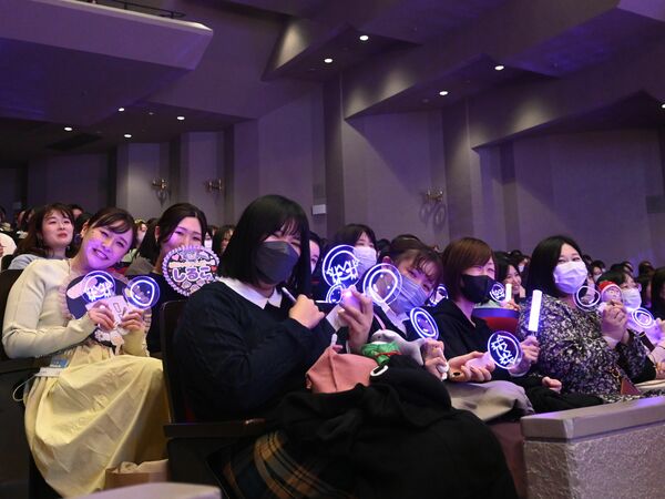 イベントグッズのペンライトやうちわを持って栃木公演を楽しむファン