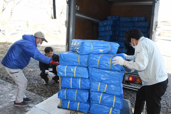 倉庫のブルーシートをトラックに積み込む益子町の職員＝４日午後２時半、益子町益子