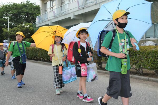 傘を差して下校する児童ら