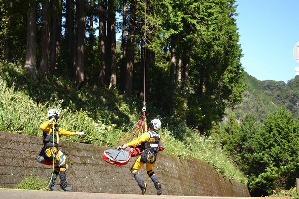 負傷者をヘリで吊り上げて救出しようとする消防隊員ら