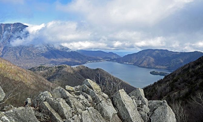 周囲の山々の中央に水をたたえる中禅寺湖。空を映し込み、その色合いは刻々と変化していく