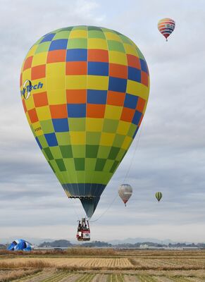 田んぼの中に設定されたターゲットに向かって低空飛行する熱気球＝17日午前８時10分、群馬県板倉町大曲