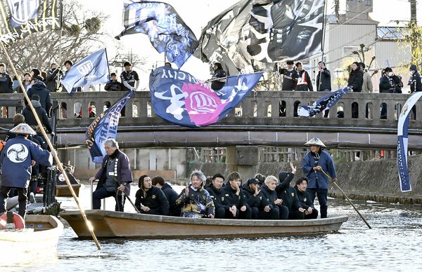巴波川橋の上でサポーターが大旗を振る中、船上パレードを行う栃木シティの選手ら＝11日午後３時30分、栃木市湊町