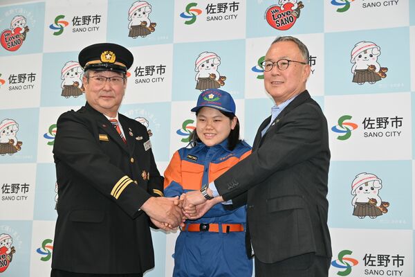 金子市長（右端）、谷市消防団長（左端）と握手する石川さん