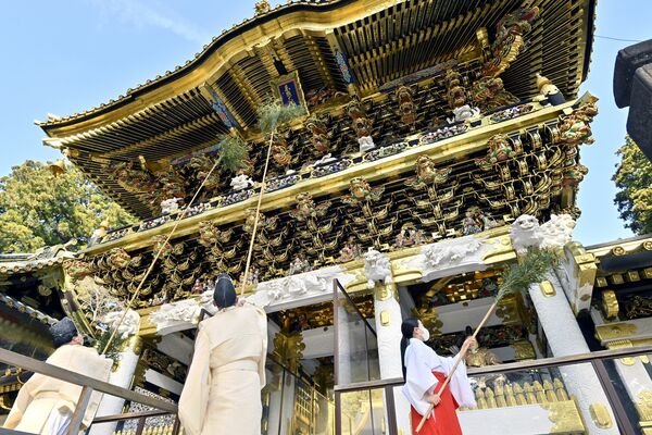 陽明門のすすを丁寧に払う神職と巫女=20日午前10時15分、日光市山内