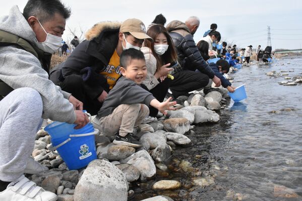放流したサケの稚魚に手を振る家族連れら