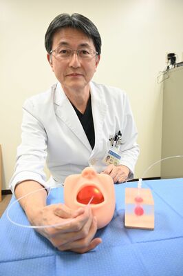光免疫療法の治療機器で模型にレーザー光を照射する野口教授＝下野市薬師寺