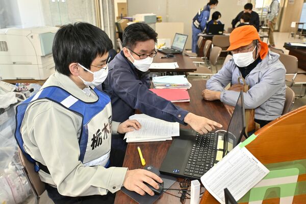 行政支援で石川県に入り、穴水町職員の岩本さん（左から２人目）と一緒に、罹災証明の手続きに携わる大田原市職員の森本和雅さん（左）＝２月27日午後３時45分、石川県穴水町