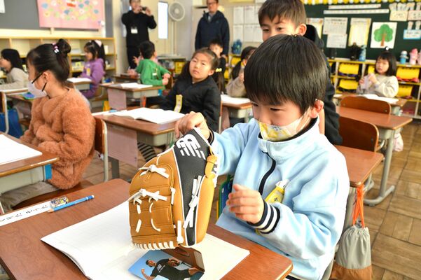 大谷選手から届いたグラブを手に取る児童