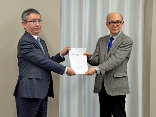 　気象庁の野村竜一長官（左）に報告書を手渡す京都大防災研究所の矢守克也教授＝２０日午後、気象庁
