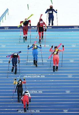 　山岳スキーの混合リレー、スキー板を外して階段を登る選手たち＝２１日、ボルミオ（ロイター＝共同）
