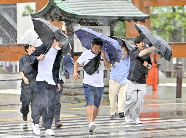 強風にあおられながら横断歩道を渡る人たち＝3日午前11時50分、宇都宮市馬場通り４丁目