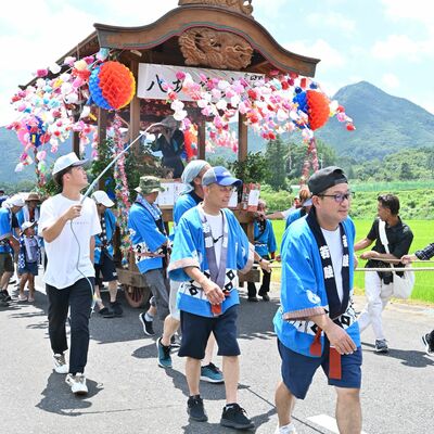 華やかに飾られた山車を元気よく引く参加者たち