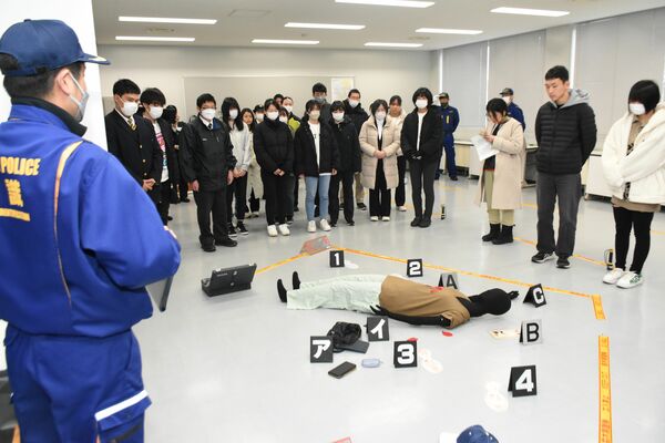 参加者らに殺人現場を想定した鑑識作業を説明する担当者（左）＝23日午前９時45分、県警察学校