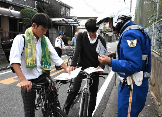 自転車で下校中の高校生に交通安全を呼びかける警察官ら＝25日午後、宇都宮市桜３丁目