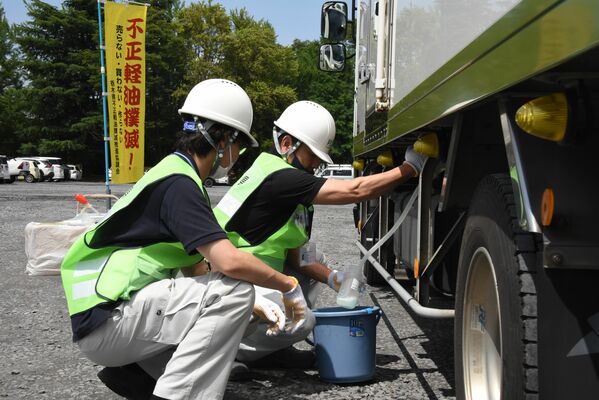 大型車両から調査用に燃料を抜き取る職員