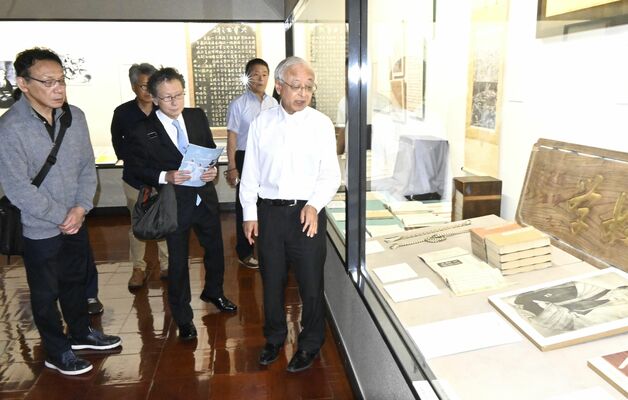 新井さん(右)の説明を聞きながら、大関増業の肖像画パネルを眺める足利さん(手前中央)