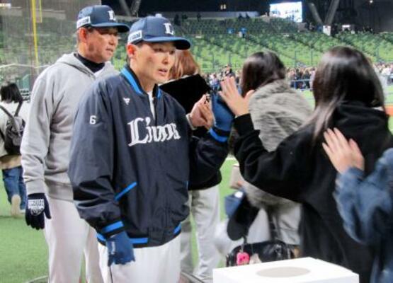 　大分市佐賀関で起きた大規模火災の被害者支援のため、募金活動を行う西武・源田。奥は鳥越ヘッドコーチ＝２３日、ベルーナドーム