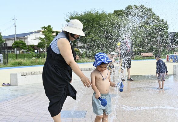 強い日差しの下、噴水で遊ぶ親子ら＝21日午後、宇都宮市錦３丁目