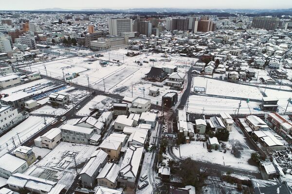 住宅の屋根や区画整理事業の工事現場に雪が積もり、白くなった宇都宮市内＝６日午前６時45分、下野新聞社屋上でドローンから