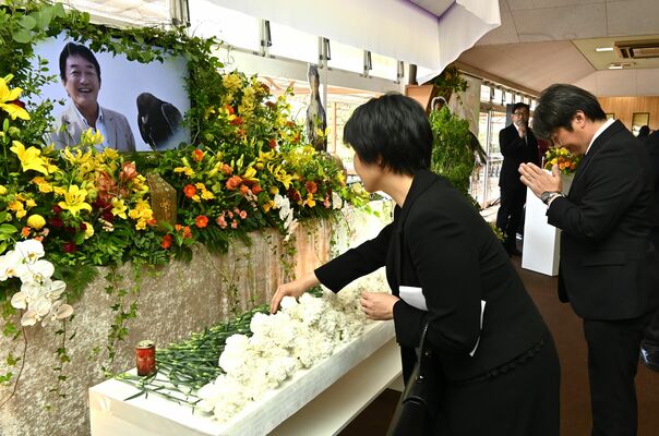 佐藤さんの遺影の前で献花する参列者