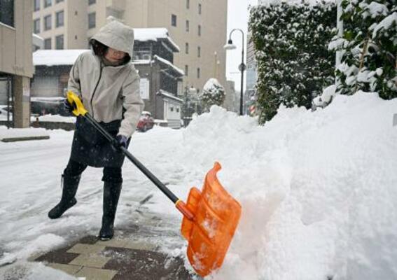 雪かきをする人=23日午前、金沢市