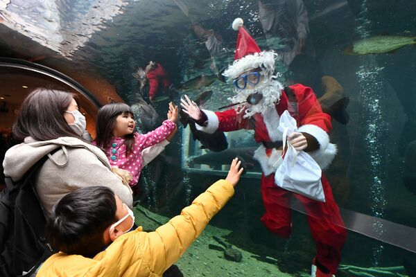 水槽の中から子どもたちに手を振るサンタクロース＝17日午前11時45分、大田原市佐良土