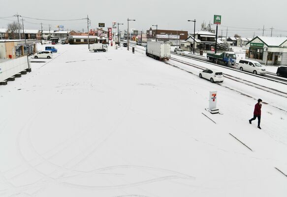 雪に覆われた駐車場と、のろのろ運転が続く国道４号＝25日午前９時30分、さくら市卯の里４丁目