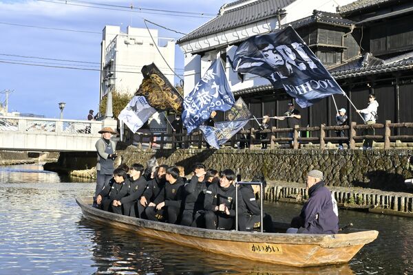 蔵が並ぶ巴波川で船上パレードする栃木シティの選手ら＝11日午後３時20分、栃木市湊町