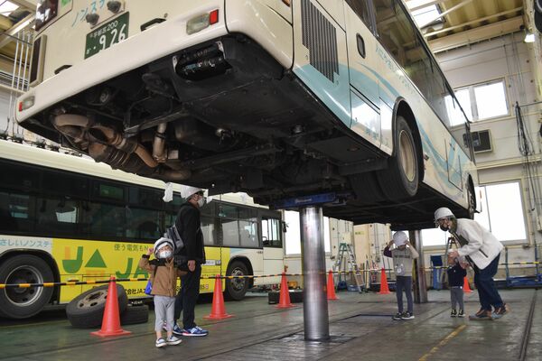 興味津々でバスの下をのぞく親子連れ＝20日午前、宇都宮市中一の沢町