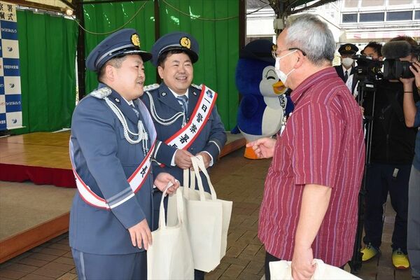 来場者に特殊詐欺被害防止の啓発グッズを手渡したザ・たっちの２人