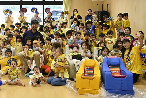 黄色と青の福祉用チェアを寄贈した竹内選手と園児ら＝27日午前、宇都宮市道場宿町
