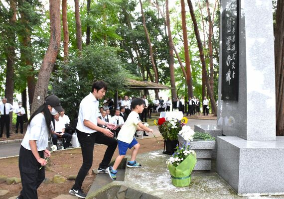 慰霊碑に献花する参列者＝24日午前、宇都宮市西川田４丁目