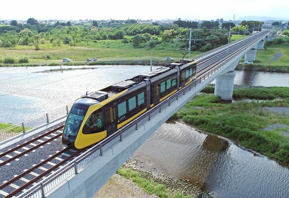 鬼怒川に架かる橋を渡るＬＲＴ。26日開業に向け全国から注目が集まる＝３日午後３時10分、宇都宮市内、ドローンから