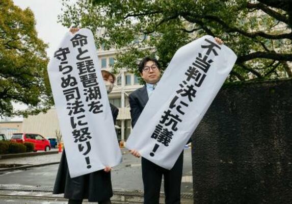 　関西電力の原発計７基の運転差し止めを求めた訴訟の判決で、垂れ幕を掲げる原告側＝２５日午後２時３分、大津地裁前