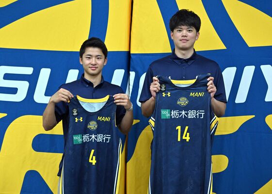 入団会見でユニホームを掲げるブレックスの四家（左）と村岸＝県庁