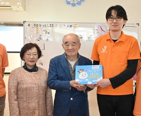 絵本を寄贈した植原会長(中央)と妻の菊枝さん(左)