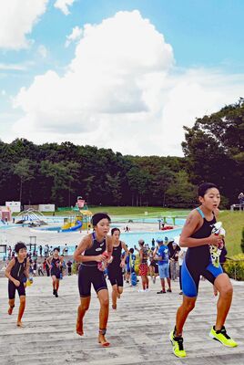 猛暑の中、一万人プール「流れるプール」のスイムからバイク（自転車）に向かう選手たち＝３日午後０時５分、井頭公園