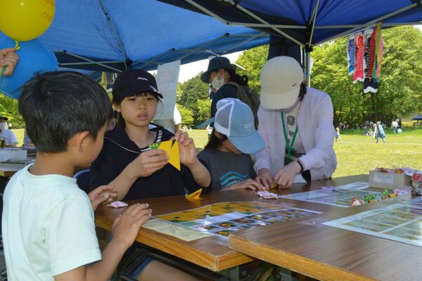 折り紙で黄ぶなを折る子どもたち＝５日午前11時50分、宇都宮市長岡町