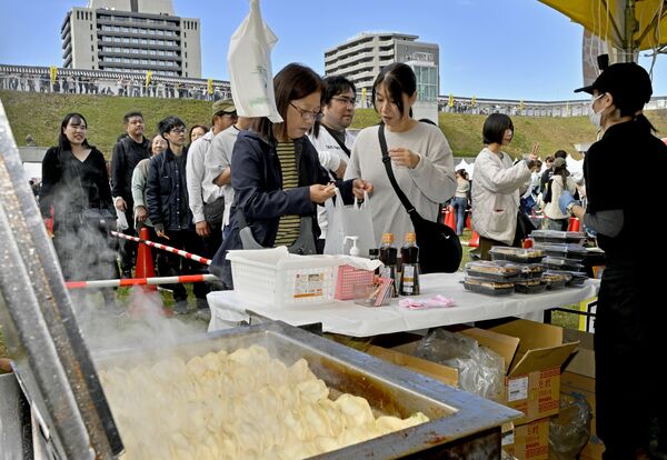 焼きたての餃子を求め行列をつくる来場者=1日午後0時10分、宇都宮市本丸町