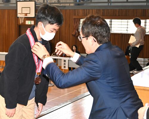 坂村市長(右)にメダルをかけてもらい表彰を受ける児童