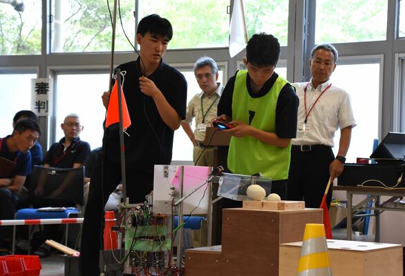 真剣な表情でロボットを操作する高校生ら