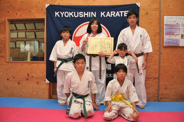 ５人の弟、妹に囲まれ、賞状を手にする高久さん（後列中央）